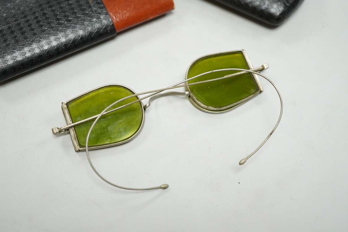 Two pairs of 19th century double D folding tinted spectacles, both cased, an unusual pair of green tinted pince nez with vulcanite side eye protectors, cased and a pair of optometrist ‘patent’ spectacles with sliding blu